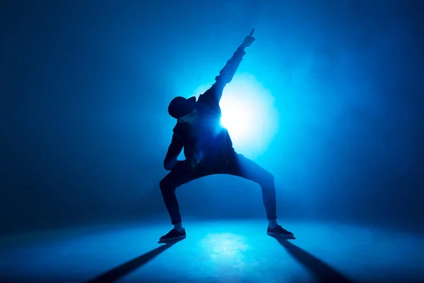 Bailarín de descanso masculino realiza en el escenario de neón azul su danza expresiva, destello de luz —  Fotos de Stock