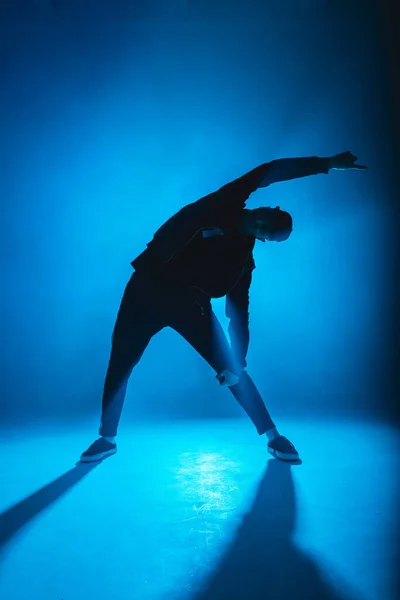 Bailarín de descanso masculino realiza en el escenario de neón azul su danza expresiva, destello de luz —  Fotos de Stock