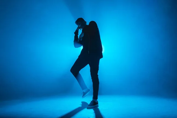 Silhueta de homem dançando no clube com relâmpago de néon azul e fumaça . — Fotografia de Stock