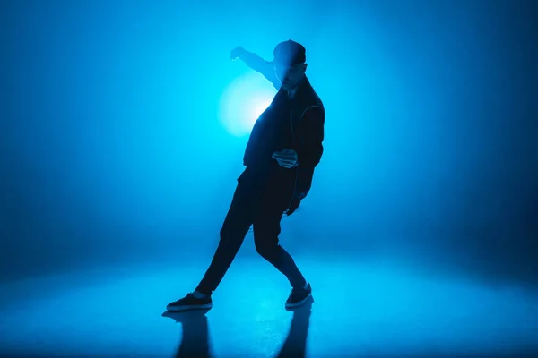 Silhueta de dançarino masculino isolado em fundo de néon azul com flare no meio — Fotografia de Stock
