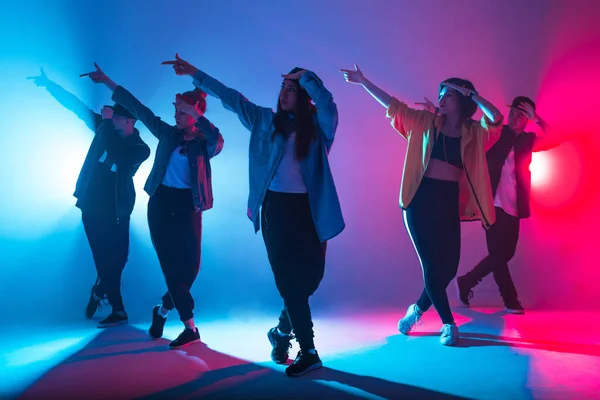 Diverso grupo de personas bailando en estudio con luz de doble color roja y azul —  Fotos de Stock