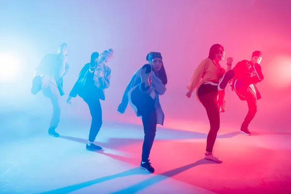 Grupo de dançarinos masculinos e femininos em luz de néon colorido se divertindo dançando . — Fotografia de Stock
