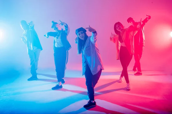 Diverse group of people dancing in studio with red and blue dual color light