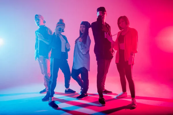 Diverso grupo de personas bailando en estudio con luz de doble color roja y azul — Foto de Stock