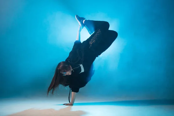 Joven bailarina de hip-hop actuando en solitario en el escenario con luces azules de neón —  Fotos de Stock