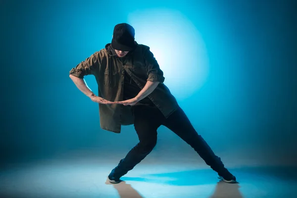 Man break danser voert op blauw neon podium zijn expressieve dans, licht flare — Stockfoto