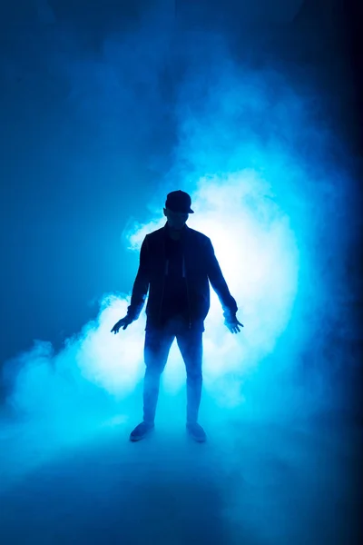 Silhueta de homem dançando no clube com relâmpago de néon azul e fumaça . — Fotografia de Stock