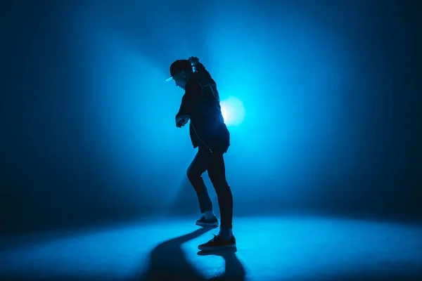 Silueta de hombre bailando en club con rayo de neón azul y humo. —  Fotos de Stock