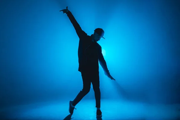 Bailarín de descanso masculino realiza en el escenario de neón azul su danza expresiva, destello de luz —  Fotos de Stock