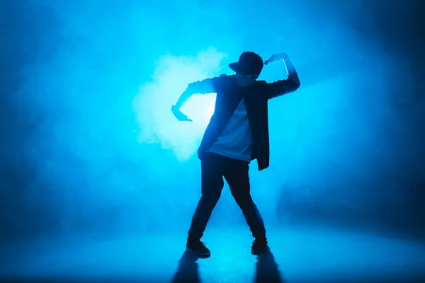 İzole edilmiş neon mavi arka planda hip hop dansı yapan genç bir dansçı. — Stok fotoğraf
