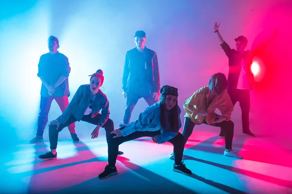 Grupo de bailarines masculinos y femeninos en colorida luz de neón divirtiéndose bailando. — Foto de Stock