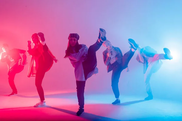 Разнообразная группа людей танцует в студии с красным и синим двухцветным светом — стоковое фото