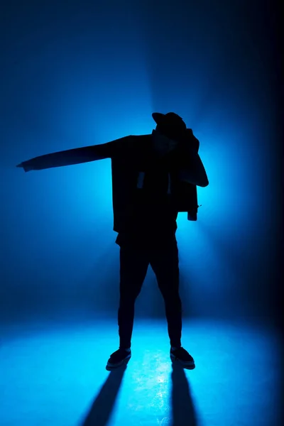 파란색 네온 배경에 가운데에 조명탄이 붙어 있는 남성 댄서 실루엣 — 스톡 사진