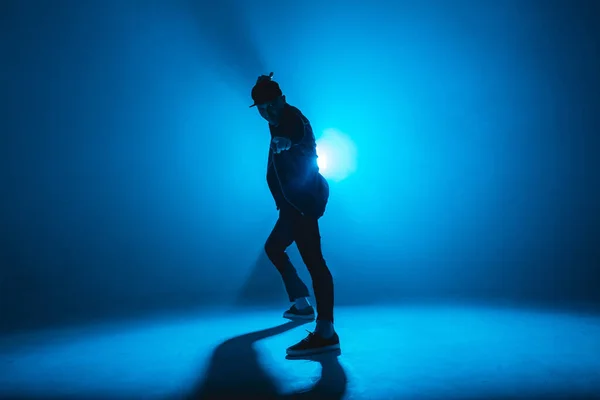 Man break danser voert op blauw neon podium zijn expressieve dans, licht flare — Stockfoto