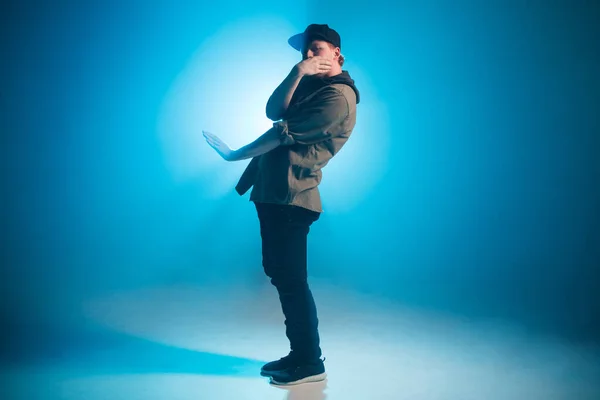 Sportowy nowoczesny styl hip-hop tancerz pokazuje swój taniec na niebieskim tle studio. — Zdjęcie stockowe