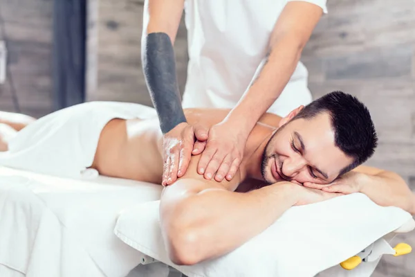 talented masseur massaging a mans sore back