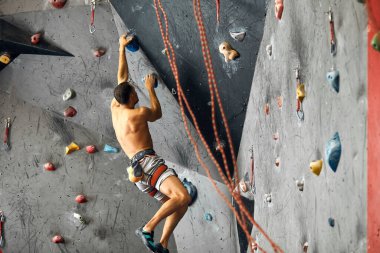 Kapalı bir tırmanma merkezinde panoramik bir adam kaya kayası yapıyor..