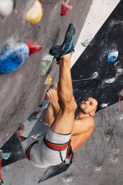 Erkek profesyonel dağcı, kayalık merkezde kapalı alanda çalışıyor..