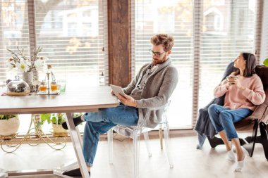 Mutfaktaki çift bir fincan kahve ve akıllı telefonla vakit geçiriyor.