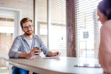 Çift fikir paylaşıyor, büyük pencerenin karşısında oturuyor..