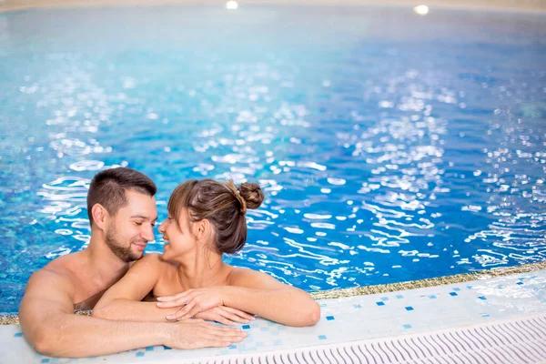 Jovens amantes alegres que passam grande tempo na piscina. — Fotografia de Stock