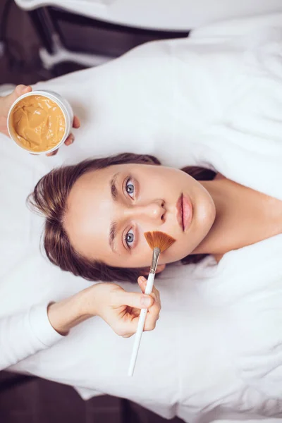 Ovanifrån porträtt av vacker ung kvinna som tar SPA, liggande på massagebord — Stockfoto