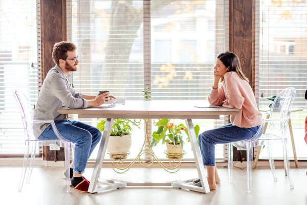 Un homme et une femme sont assis à une table en face de l'autre. — Photo