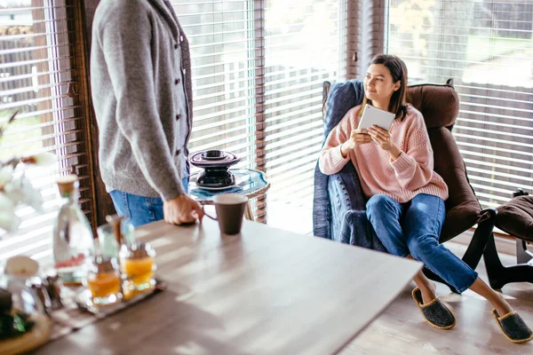 Couple in kitchen spending time together with cup of coffee and smartphone