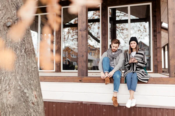 Feliz joven pareja sentada al aire libre, frente a su nuevo hogar en el día de otoño —  Fotos de Stock