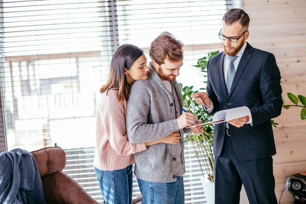 Pareja de clientes firmando papeles con corredor de hipotecas haciendo acuerdo de compra — Foto de Stock