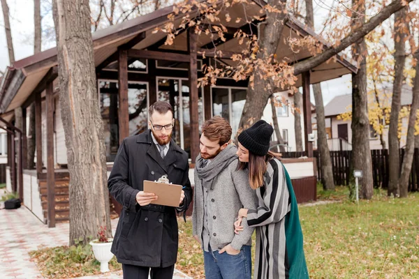 Real-estate agent with young caucasian happy couple buying new house — Stock Photo, Image