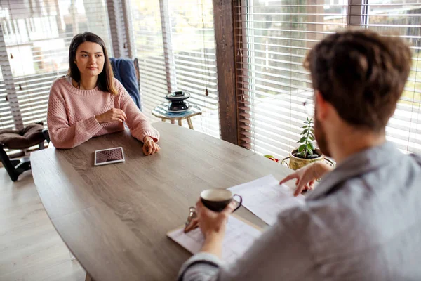 Un hombre y una mujer están sentados en una mesa uno frente al otro. — Foto de Stock