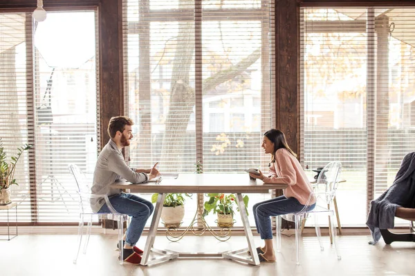 Un hombre y una mujer están sentados en una mesa uno frente al otro. — Foto de Stock