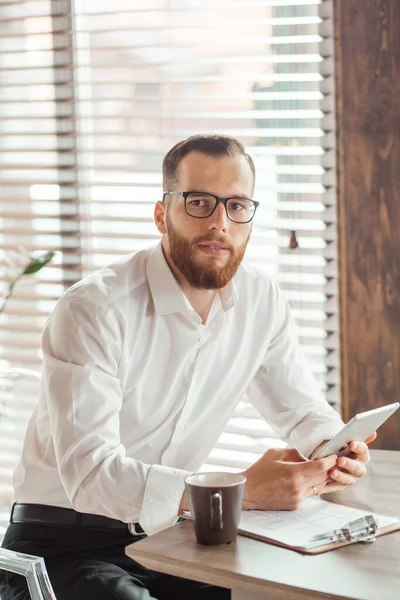 Jonge Europeaan die documenten leest terwijl hij thuis aan tafel zit — Stockfoto