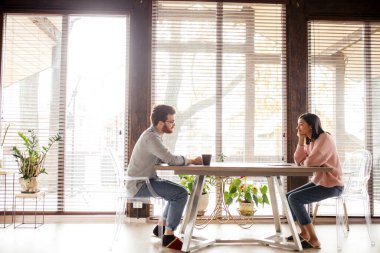 Çift fikir paylaşıyor, büyük pencerenin karşısında oturuyor..