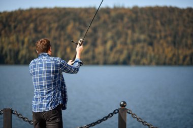 Nehir kenarında durup balık tutmaya çalışan balıkçılar.