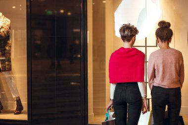 İki kadın kadınların önünde dikiz aynasından butik koleksiyonu yapıyor..
