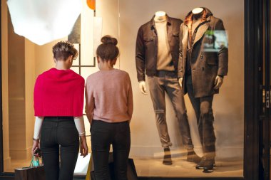 İki kadın kadınların önünde dikiz aynasından butik koleksiyonu yapıyor..