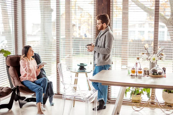 Pareja en la cocina pasar tiempo junto con una taza de café y teléfono inteligente —  Fotos de Stock