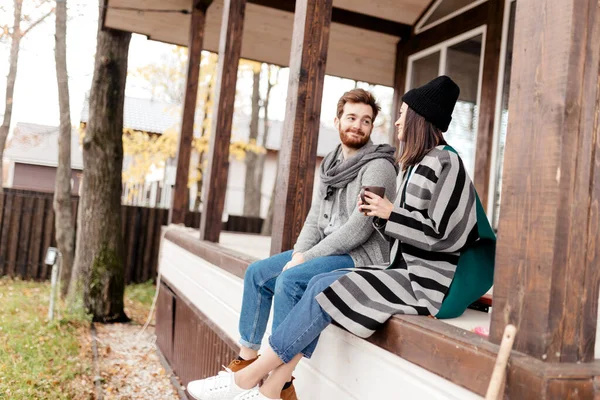 Feliz jovem casal sentado ao ar livre, na frente de sua nova casa no dia de outono — Fotografia de Stock
