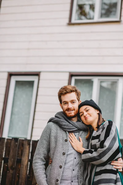 Щаслива молода пара сидить на вулиці, перед своїм новим будинком в осінній день — стокове фото