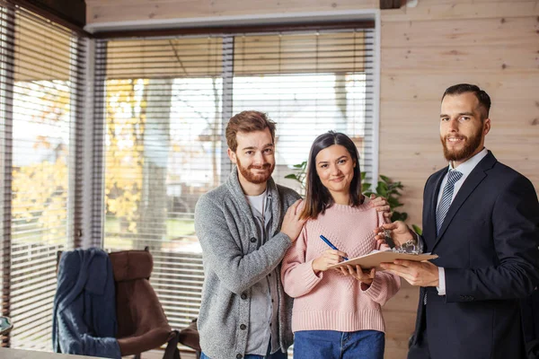 Pareja de clientes firmando papeles con corredor de hipotecas haciendo acuerdo de compra — Foto de Stock