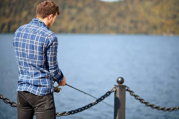 Рибалка стоїть на березі річки і намагається ловити рибу — стокове фото