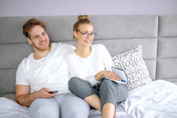 Atrakcyjna dziewczyna i facet oglądają film razem podczas odpoczynku na łóżku — Zdjęcie stockowe