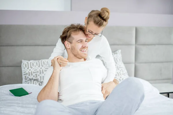 Two young people laughing while sitting on the bed — Stock Photo, Image