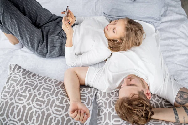 Blond meisje liggend op de fair0haired man en het maken van een telefoontje — Stockfoto