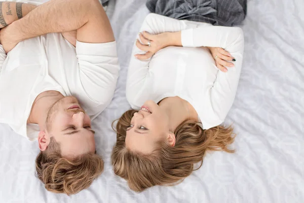 Zwei junge glückliche Menschen flirten auf dem Bett — Stockfoto