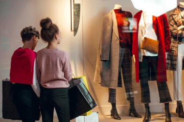 İki kadın kadınların önünde dikiz aynasından butik koleksiyonu yapıyor..