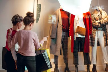 İki kadın kadınların önünde dikiz aynasından butik koleksiyonu yapıyor..