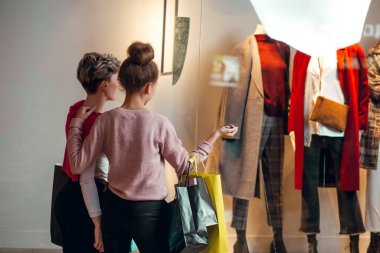 İki kadın kadınların önünde dikiz aynasından butik koleksiyonu yapıyor..